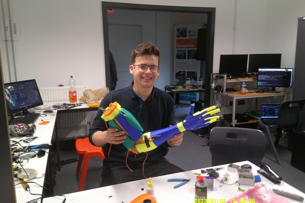UTC OLP student holding a robotic arm he has been working on as part of work experience
